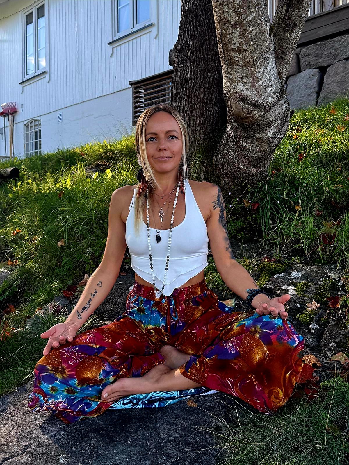 Lina, founder of Shining Light Tantra, seated in meditation outdoors
